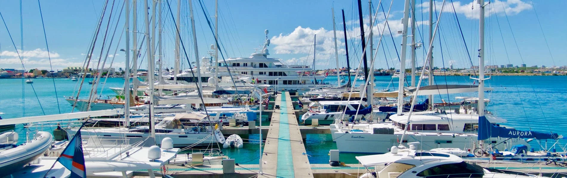 Yachts and sailboats moored in a bright Sint Maarten marina.
