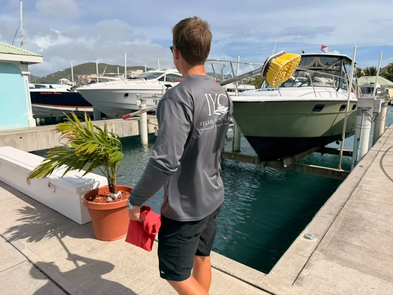 Island Yacht Care approaching a boat with cleaning equipment at a Sint Maarten marina.